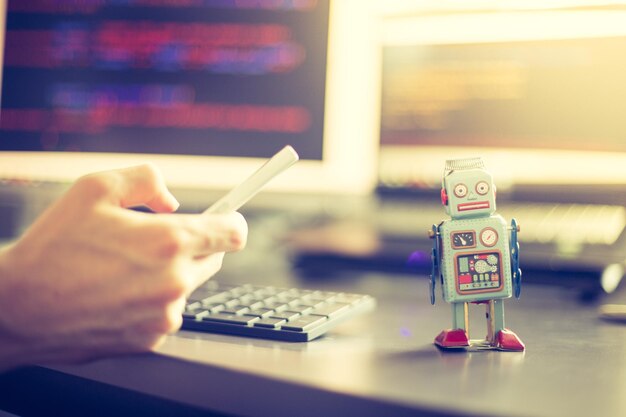 チャットボットまたはソーシャル ボットのシンボルと、バックグラウンドでのアルゴリズム プログラム コード