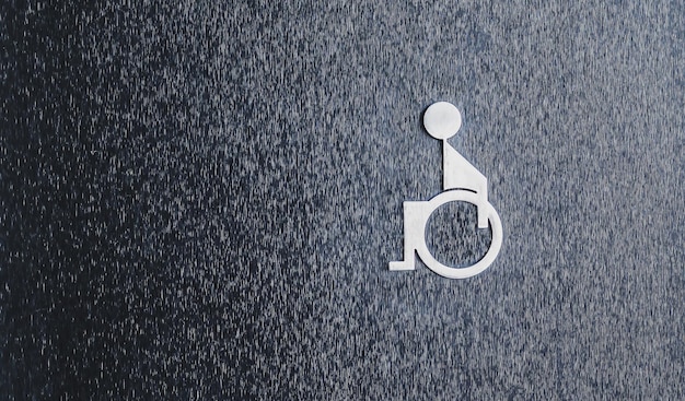 Il simbolo della toilette per disabili sul muro nero