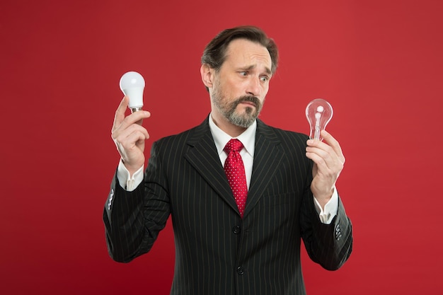 Symbol of idea progress and innovation Idea for business Environment friendly idea Genius idea Light up your business Man bearded businessman formal suit hold light bulb on red background