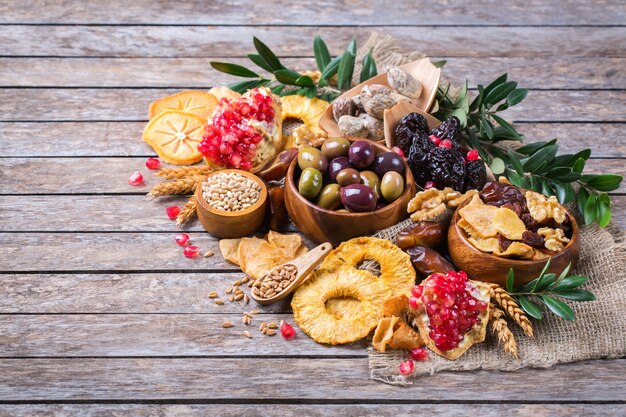 Symbolen van judaic vakantie Tu Bishvat, Rosh Hashana nieuwjaar van de bomen. Mix van gedroogde vruchten, dadels, vijgen, druif, gerst, tarwe, olijven, granaatappel op een houten tafel. Ruimte achtergrond kopiëren