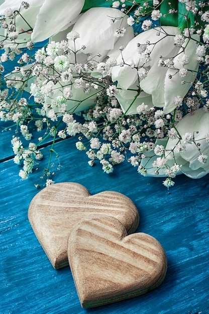 Symbolisch houten hart op de achtergrond van boeket van witte rozen