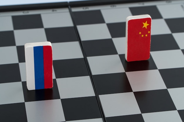 チェス盤にロシアと中国のシンボルフラグ。政治ゲームの概念。