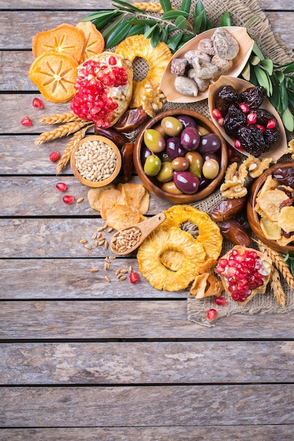 사진 유대교 휴일 tu bishvat, 나무의 rosh hashana 새해의 상징. 나무 탁자에 말린 과일, 대추, 무화과, 포도, 보리, 밀, 올리브, 석류를 섞으세요. 복사 공간 평면 누워 배경