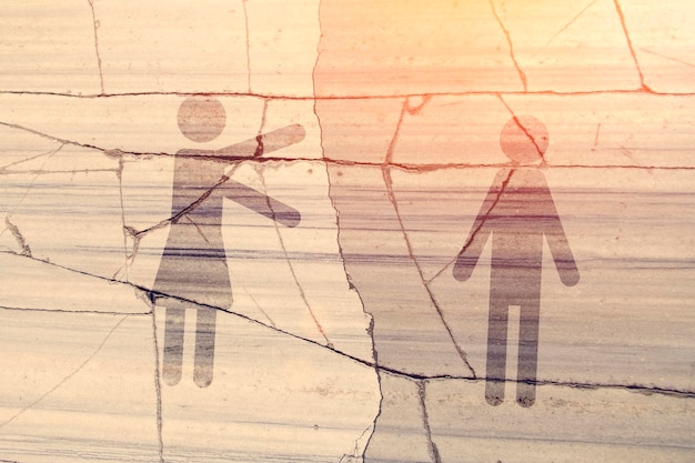 Symbols woman stretching her arms out toward the man on the background of a concrete wall divided by cracks Toned