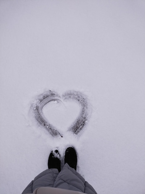 Foto symbool hart getekend in de sneeuw aan de voeten van vrouwen