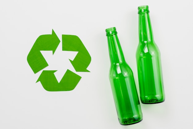 Foto symbool van recycling naast glazen flessen