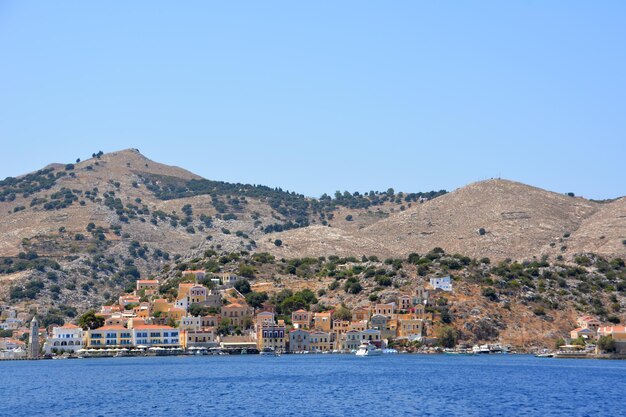 Symi island with deserted hills and waterfront with buildings isolated in sunny day