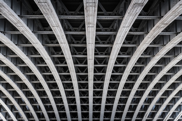 Symmetric steel framework under a bridge over the river Thames in London.