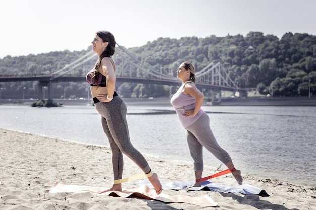 Synchrone bewegingen. Leuke jonge vrouwen die zich op yogamatten bevinden terwijl ze samen een oefening doen