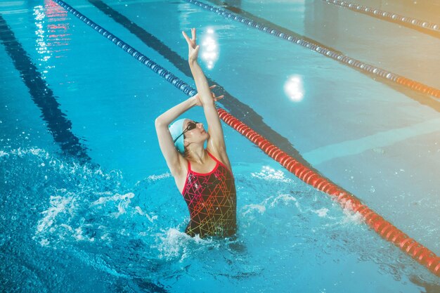 Synchronized girl working out tricks in the pool Synchronized swimming sports in the water Professional sportswoman doing exercises in the pool Training before the competition