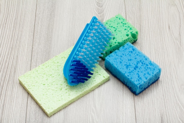 Synthetic sponges microfiber napkin and brush for cleaning on gray wooden boards