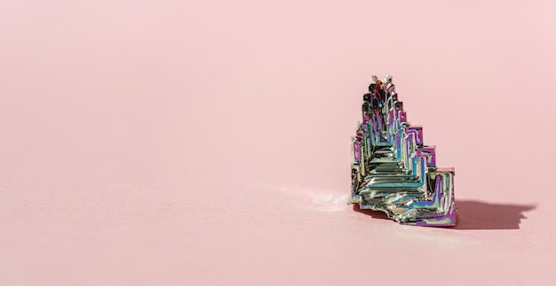 Synthetisch bismut Bismuthum kristal met iriserende oxide film op roze achtergrond close-up geïsoleerd Verbazingwekkende kleurrijke glanzende regenboog Bismut edelsteen minerale Banner
