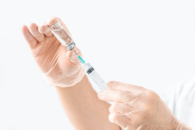 Syringe and ampoule with medicine in the hands of a doctor on a gray background