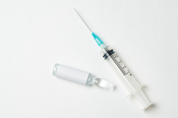 Syringe and ampoule with medicine on white background.