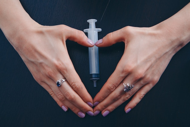 Syringe on dark . hands holding a medical device.  a healthy lifestyle, health care, drug addiction, vaccination. 