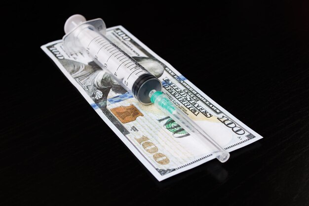 Syringe and dollars on a wooden table