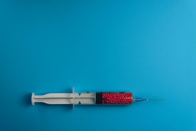 Syringe filled with colorful nano balls on a blue background Innovative medical concept
