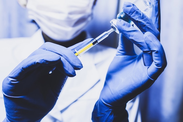 Syringe and hand closeup. The concept of vaccination, filling the drug into the syringe. Doctor background