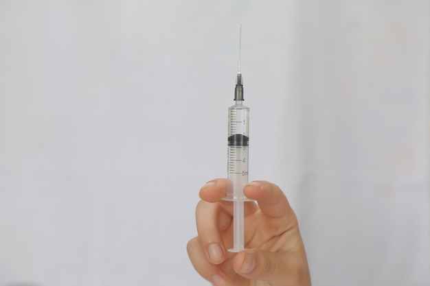 syringe in the hand of a young woman on a white background