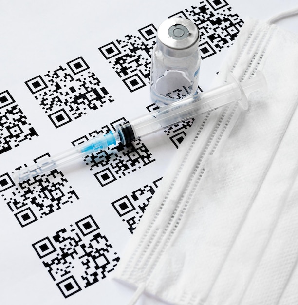 syringe, mask and vaccine on the background of qr codes. medical concept.
