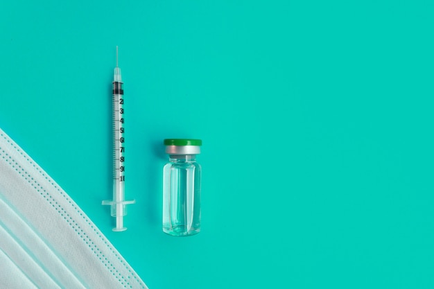 Syringe, medical mask and ampoule with medicine on a blue background