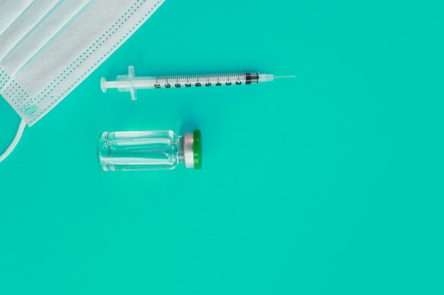 Photo syringe, medical mask and ampoule with medicine on a blue background