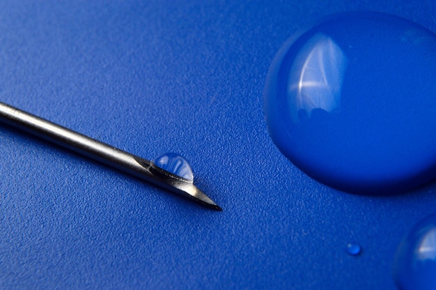 Photo syringe needle and a drop of a transparent substance closeup