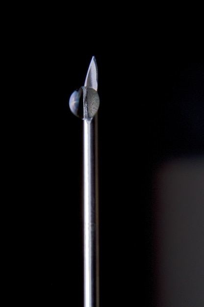 Syringe needle and a drop of a transparent substance closeup