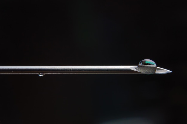 Syringe needle and a drop of a transparent substance closeup