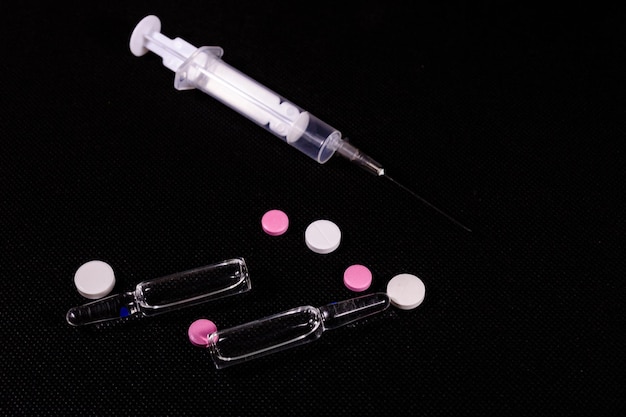 Syringe and pills on a black background Healthcare and medicine concept