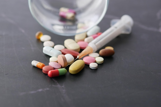 Syringe and pills on dark background close up