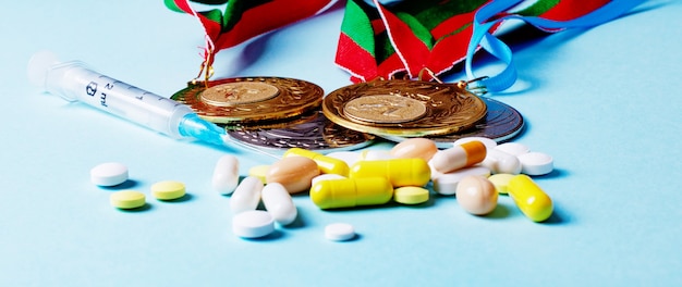 Syringe, pills and medals on a blue background. doping in sports. abuse of anabolic steroids for sports. sports fraud. doping athletes