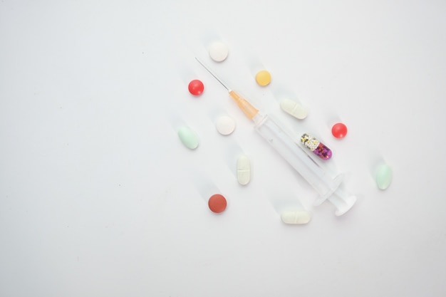 syringe and pills on white background, top view