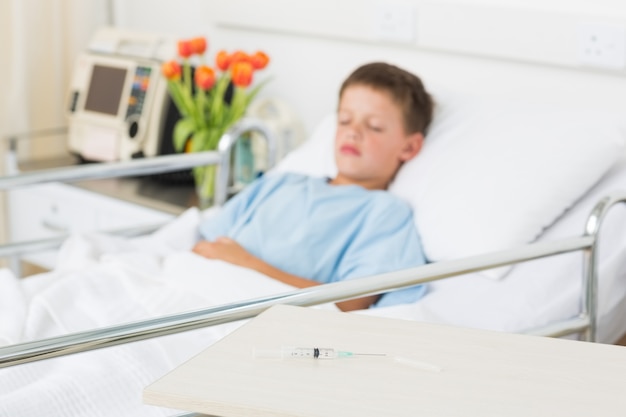 Syringe on table with boy in hospital ward