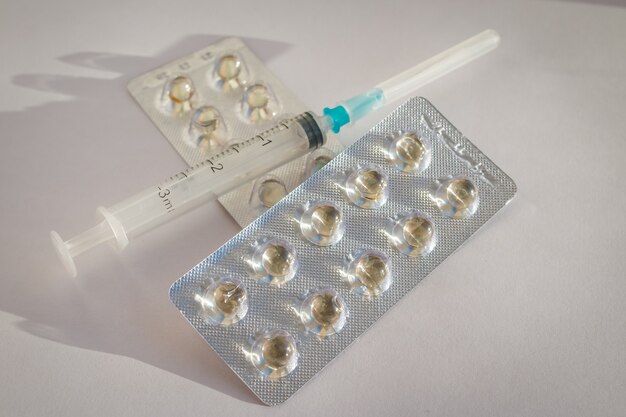 syringe, vitamins, dragee on the white background.