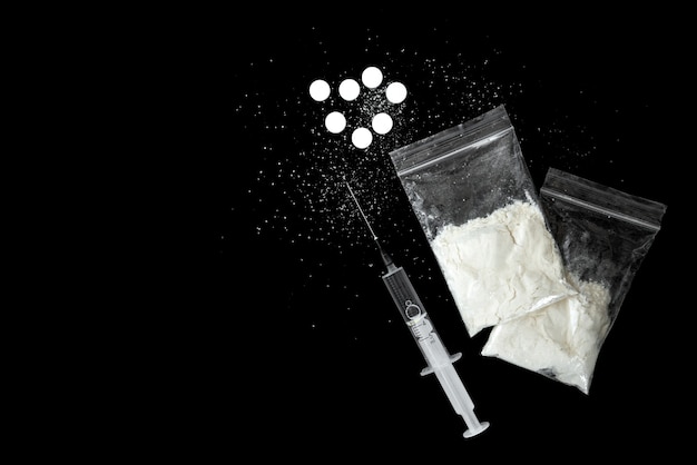 Photo syringe and white pills on black