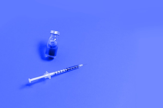 Photo syringe with blue medicine liquid on blue background. vaccination and immunity