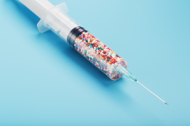 A syringe with colored balls on a blue