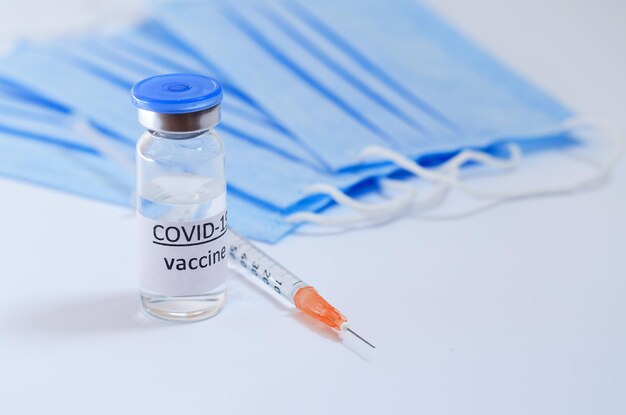 syringe with medical masks and vaccine vial glass bottles. vaccination against COVID-19. Coronavirus