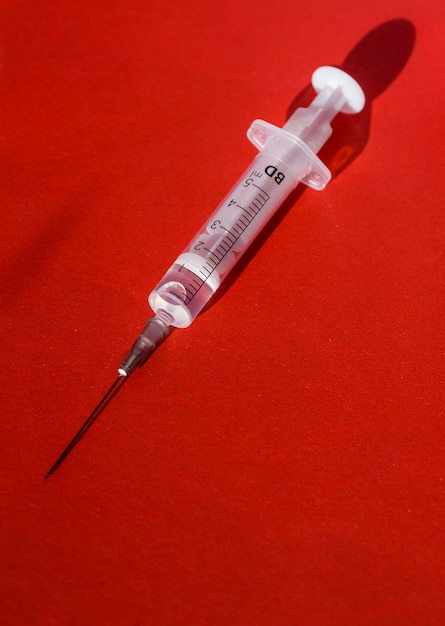 A syringe with a medicine on a red background with a tit-for-tat.