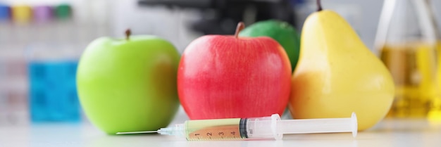 Syringe with medicines lying near fruit on background of microscope closeup genetic engineering