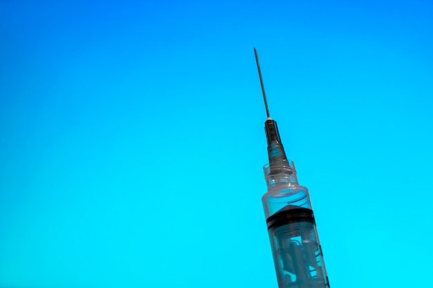 Syringe with needle on blue background vaccine