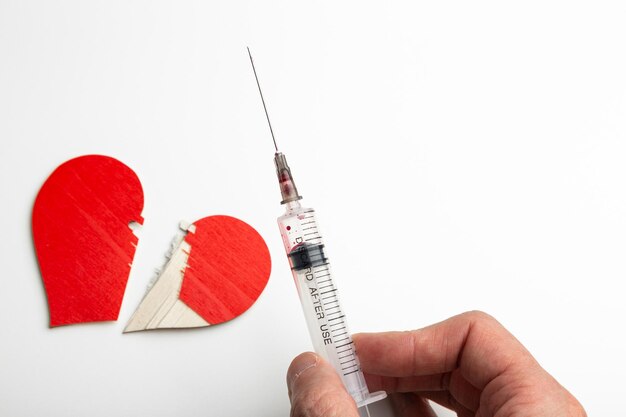 A syringe with a needle and a broken heart drug addiction