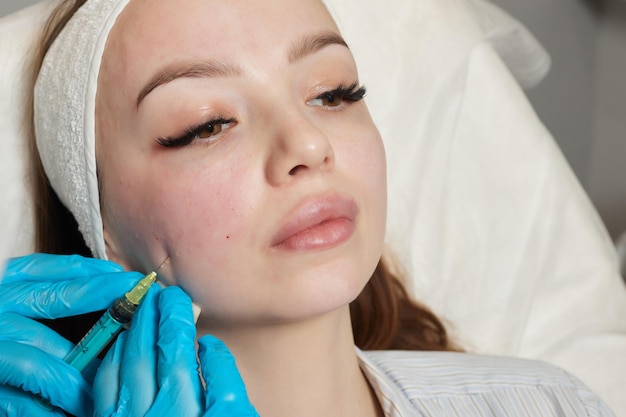 Syringe with a patients blood plasma in a cosmetologists hand for a plasmolifting of a womans facial