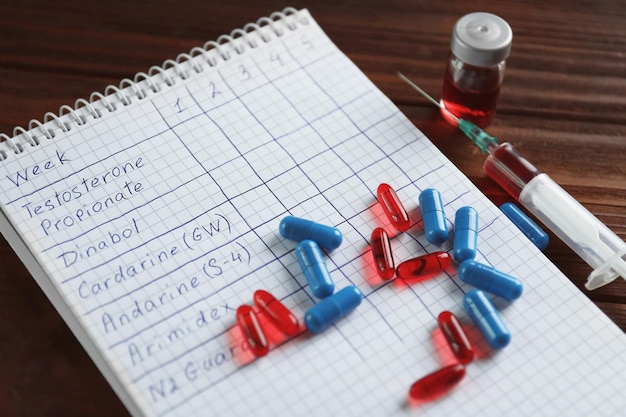 Photo syringe with pills and notebook doping in sport concept