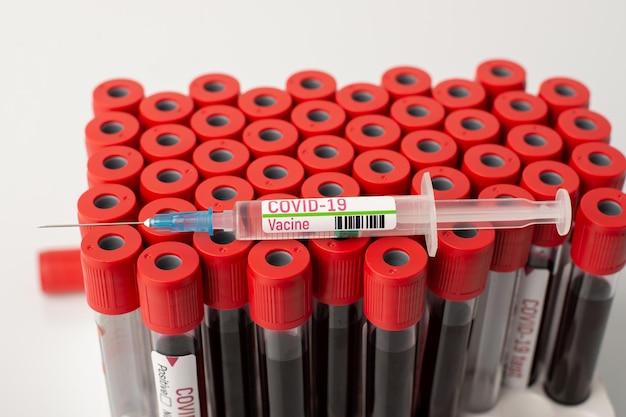 Syringe with vaccine against Covid19 virus on pack with blood tests