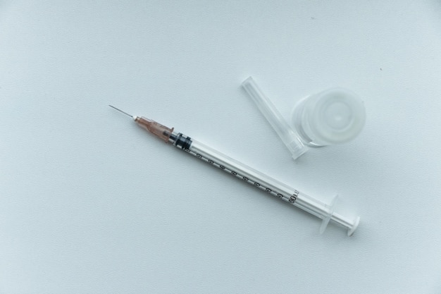 ワクチンの入った注射器 白いテーブルの上のアンプル