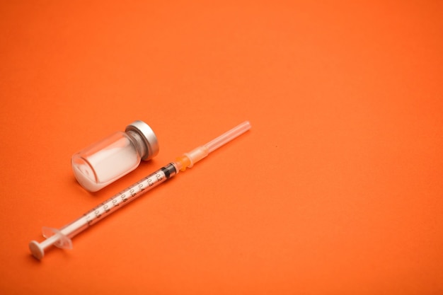 syringe with vaccine bottle, blue surface