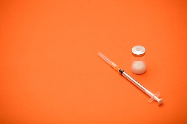 syringe with vaccine bottle, blue surface