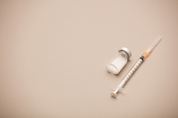 syringe with vaccine bottle, brown background